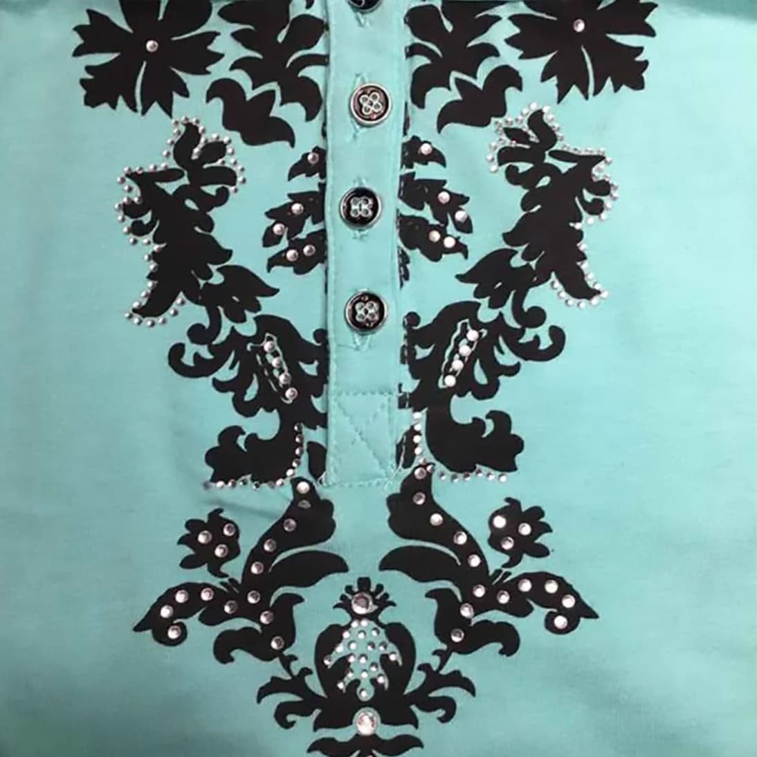 Primer plano de los botones metálicos, el bordado floral y las brillantes piezas de strass.