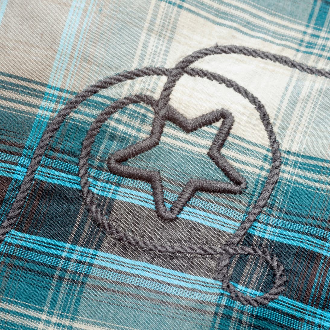 Primer plano del bordado artesanal en el pecho de la camisa de cuadros Josie.