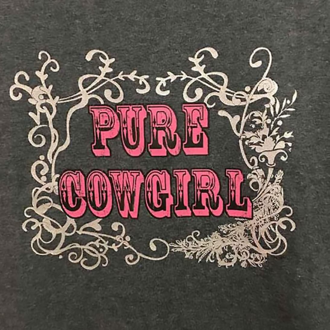 Primer plano de la impresión tipográfica Pure Cowgirl sobre el tejido gris oscuro.
